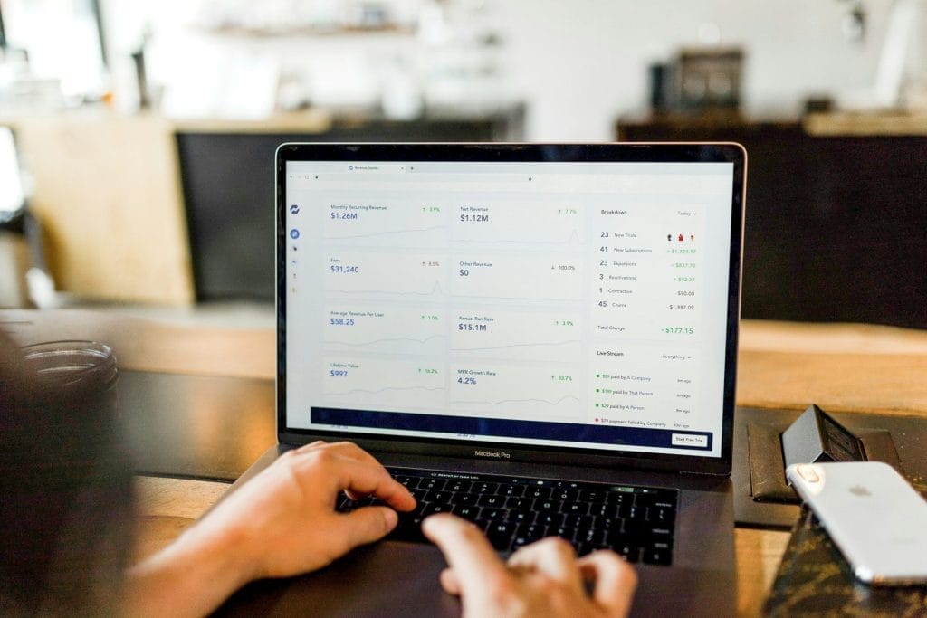 Dynamic Pricing Software: The picture shows a laptop on the kitchen counter in an Airbnb. The screen shows a dashboard with sales growth curves.