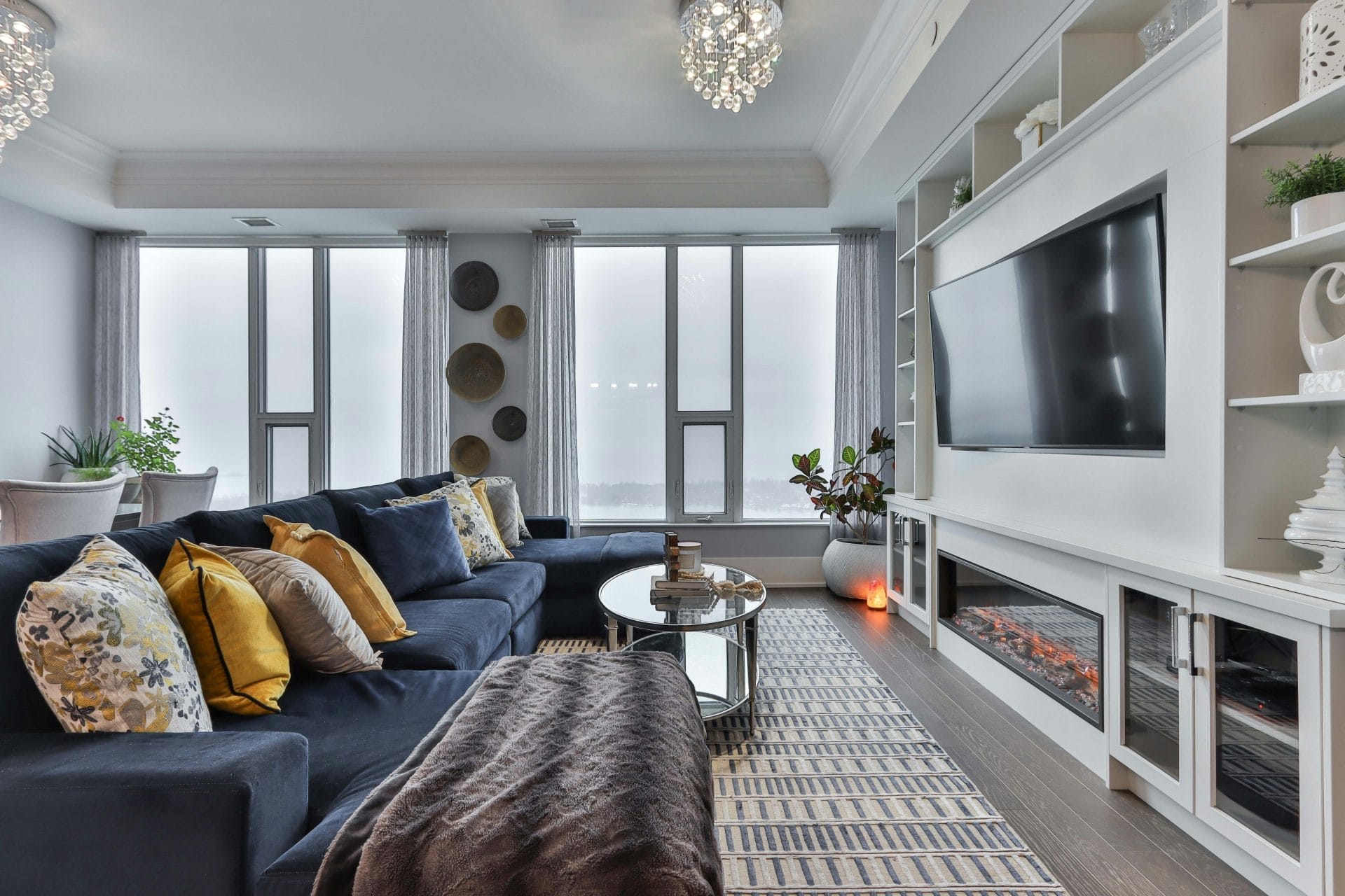 High-End Airbnb Guests: The image shows a large living room with a navy blue couch and lots of decoration in front of a large TV.