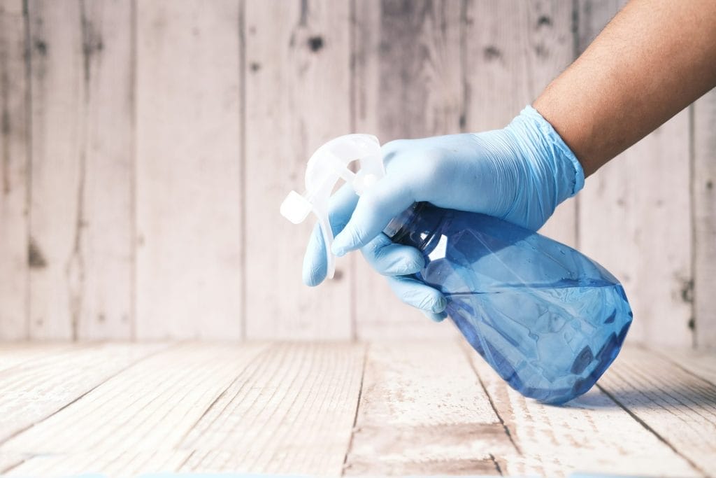 One way to improve guest satisfaction: A woman is holding a cleaning spray bottle over a table.